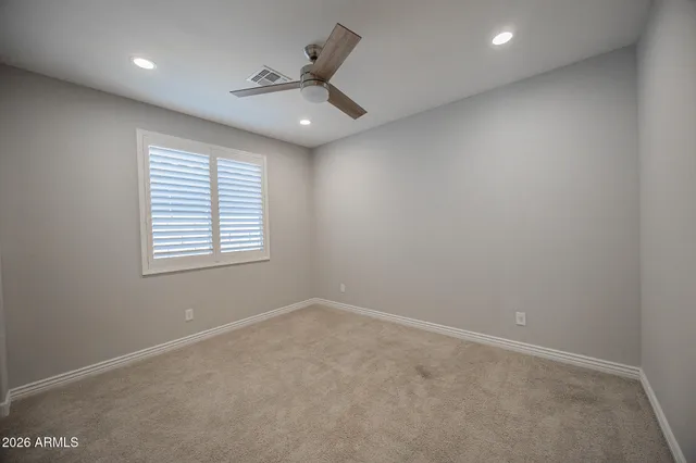an empty room with a window and a fan
