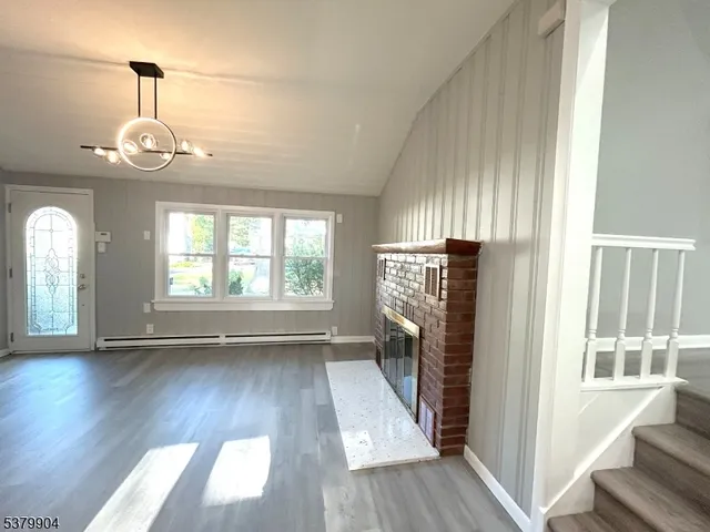 an empty room with wooden floor fireplace and windows