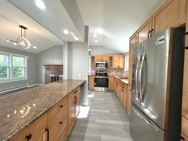 a large kitchen with kitchen island a large counter top space a sink stainless steel appliances and cabinets