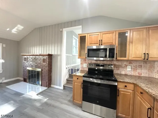 a kitchen with granite countertop a stove top oven microwave and refrigerator