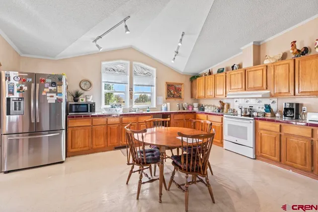 a kitchen with stainless steel appliances granite countertop a stove a sink dishwasher and a refrigerator with wooden cabinets