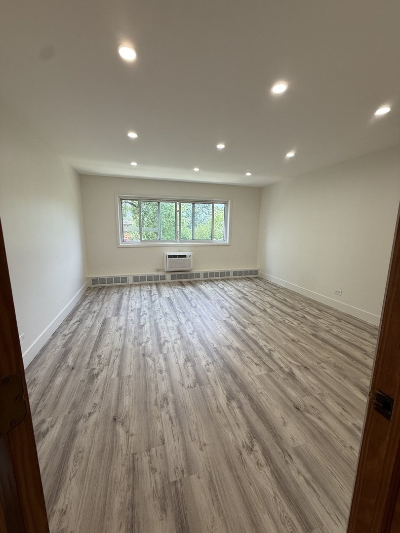 728 Dempster Street, Unit 210 Mount Prospect, IL 60056 - Photo 13 of 27 an empty room with wooden floor and windows