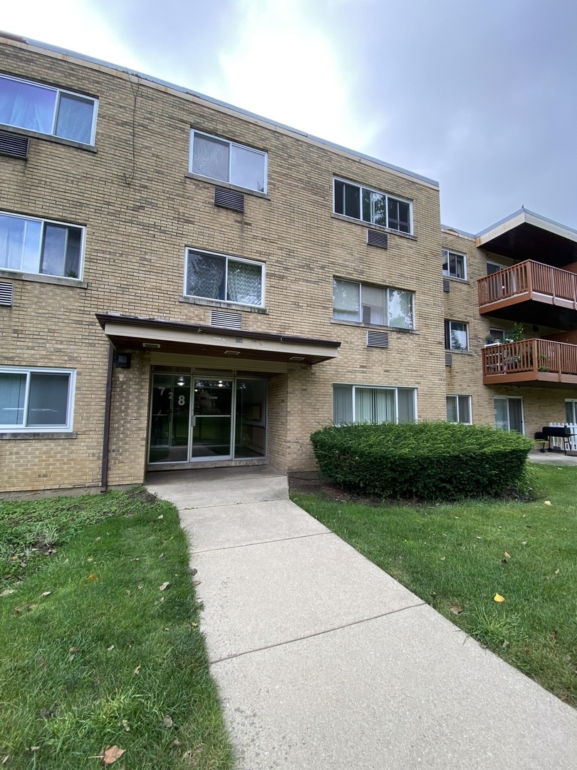 728 Dempster Street, Unit 210 Mount Prospect, IL 60056 - Photo 2 of 27 a front view of a building with a garden