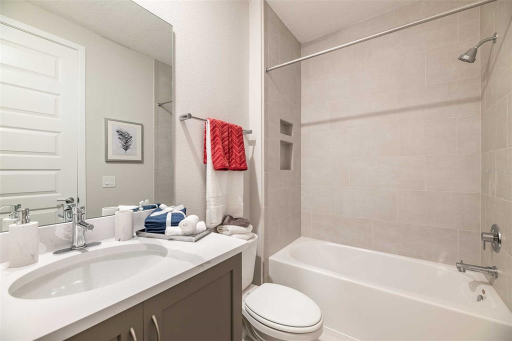 7905 Spectrum Drive Kissimmee, FL 34747 - Photo 11 of 12 a bathroom with a granite countertop bathtub shower sink vanity mirror and toilet