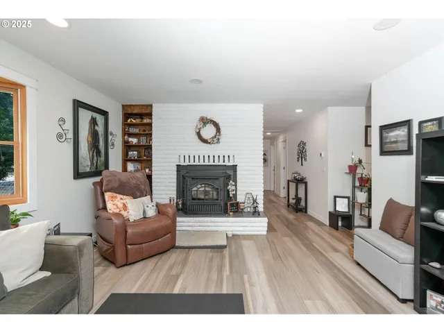 a living room with furniture a fireplace and a dining table with wooden floor