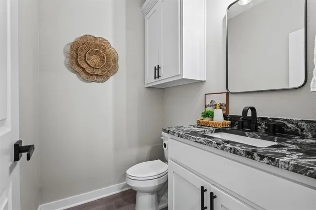 a bathroom with a granite countertop sink and a toilet