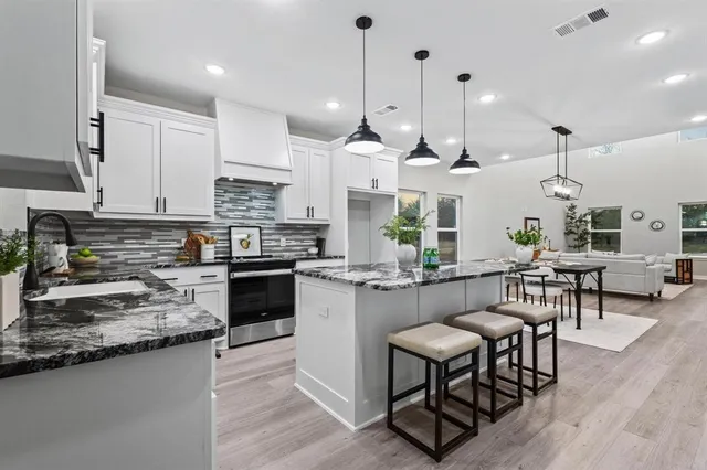 a kitchen with stainless steel appliances kitchen island granite countertop a stove a sink a oven a dining table and chairs