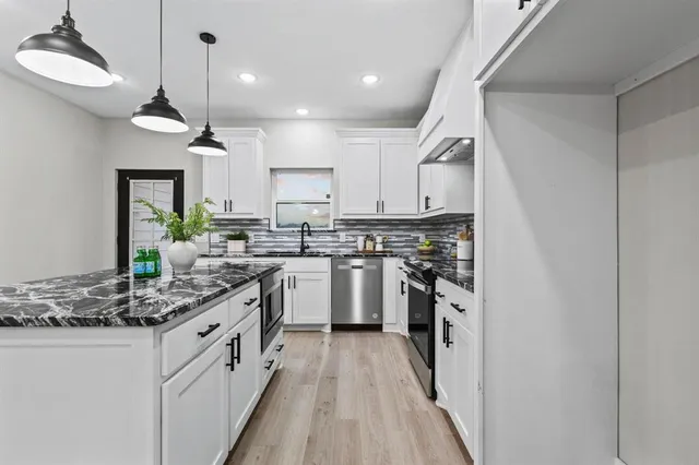 a kitchen with stainless steel appliances granite countertop a sink a stove and a refrigerator