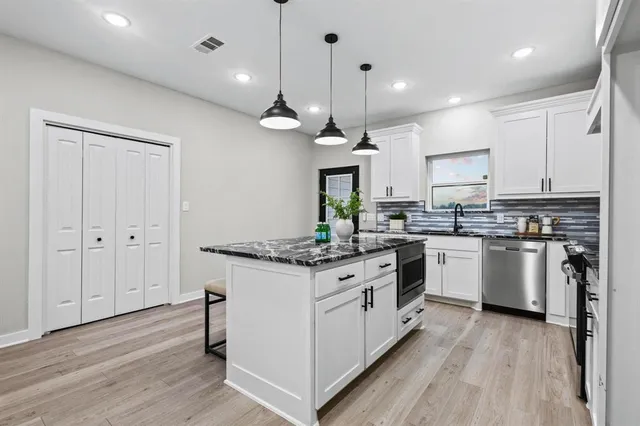 a kitchen with stainless steel appliances granite countertop a stove oven and white cabinets