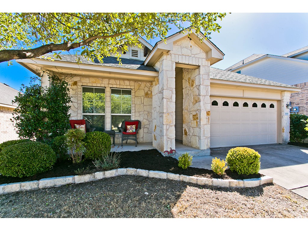 1808 Sand Creek Road Cedar Park, TX 78613 - Photo 2 of 25 Stone facade residence featuring a covered entry, an attached single-bay garage with arch-detail windows, a front porch, and mature landscaping