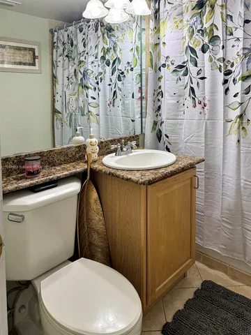 a bathroom with a granite countertop sink and a toilet