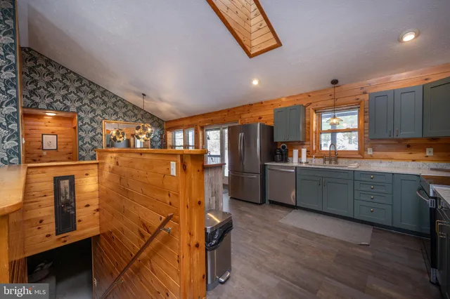 a kitchen with granite countertop a refrigerator a sink a stove and wooden floors