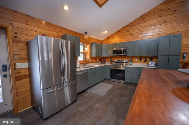 a kitchen with stainless steel appliances a refrigerator a sink a stove a microwave and wooden floors