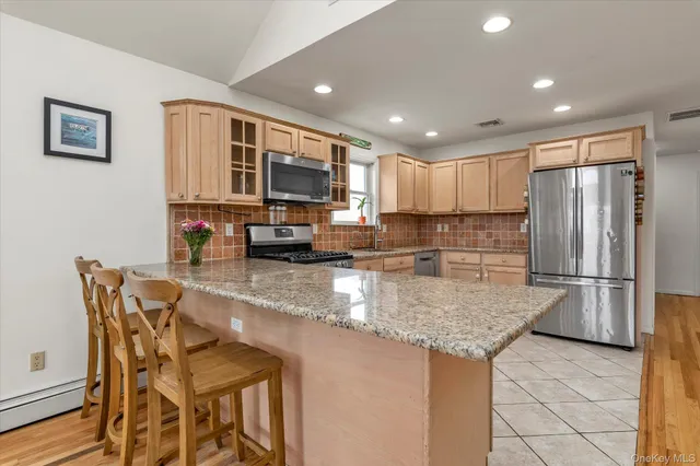 a kitchen with stainless steel appliances granite countertop a refrigerator a stove a sink a dining table and chairs