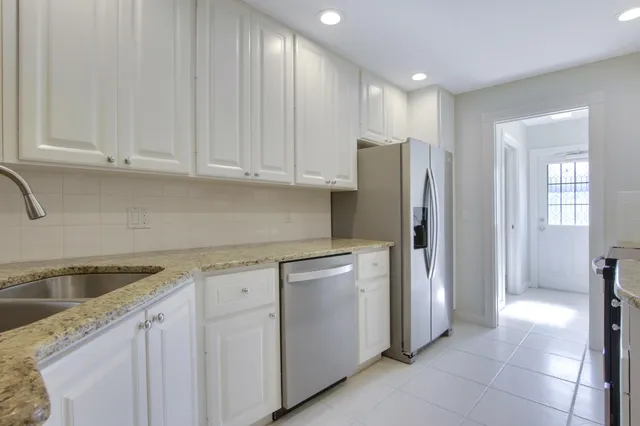 a kitchen with stainless steel appliances granite countertop white cabinets and refrigerator