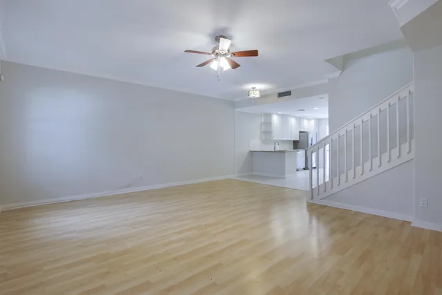 a view of an empty room with wooden floor and a ceiling fan