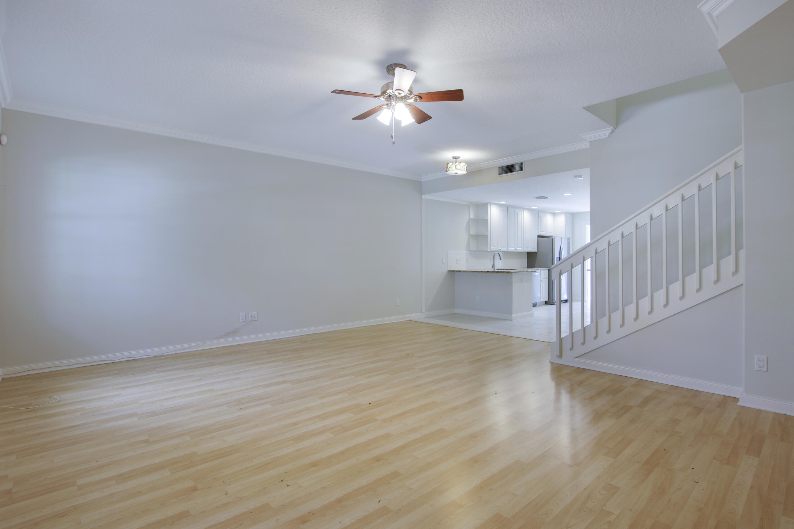 3057 East Community Drive Jupiter, FL 33458 - Photo 7 of 23 a view of an empty room with wooden floor and a ceiling fan