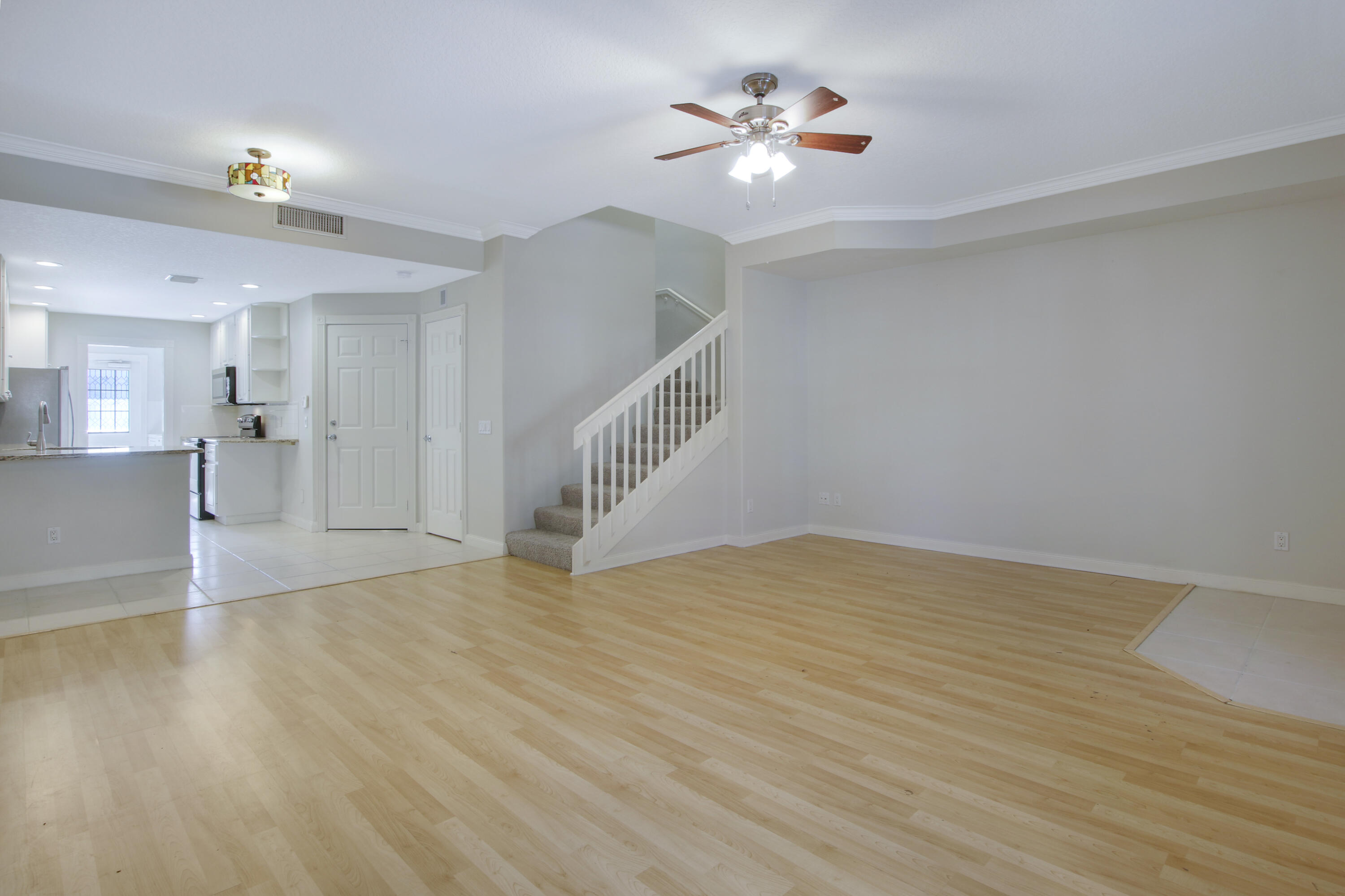 3057 East Community Drive Jupiter, FL 33458 - Photo 8 of 23 a view of an empty room with wooden floor and a kitchen