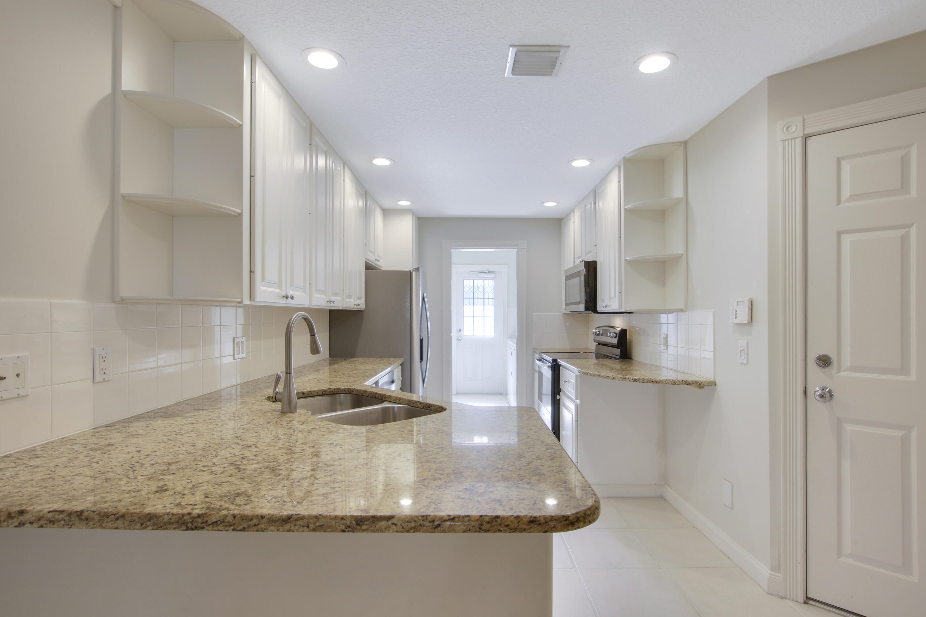 3057 East Community Drive Jupiter, FL 33458 - Photo 10 of 23 a kitchen with kitchen island granite countertop a sink a stove and cabinets