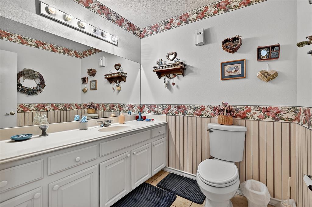 929 County Line Church Road Whitesboro, TX 76273 - Photo 20 of 38 a bathroom with a granite countertop toilet sink and mirror