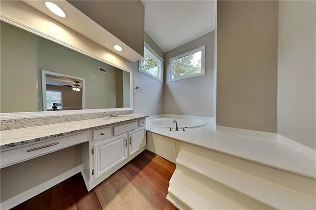 a spacious bathroom with a granite countertop sink mirror and bathtub