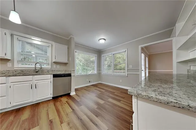 a large kitchen with granite countertop a stove a sink and a granite countertops with wooden floor