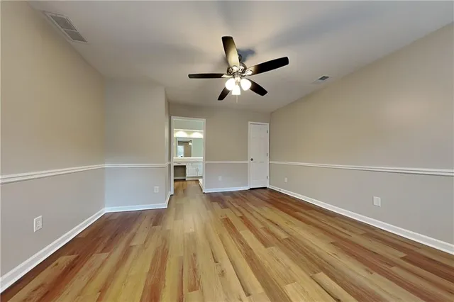 a view of empty room with wooden floor and fan