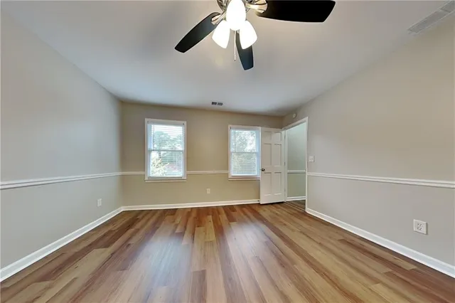 a view of empty room with wooden floor and fan
