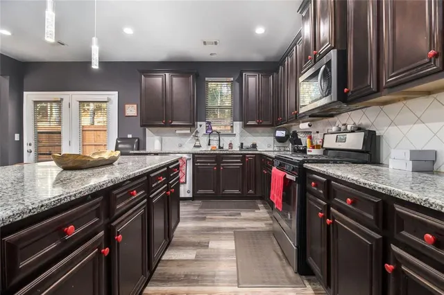 a kitchen with stainless steel appliances granite countertop a sink a stove and a refrigerator