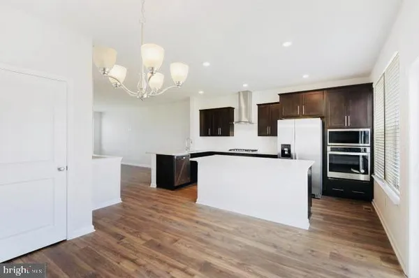 a large kitchen with stainless steel appliances a large counter top a refrigerator and a stove top oven