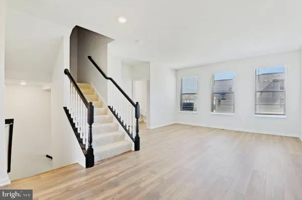 a view of an empty room with wooden floor and stairs