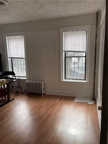 a view of an empty room with a window and wooden floor