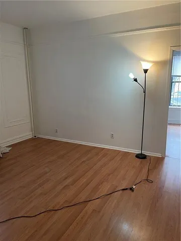 an empty room with wooden floor and window