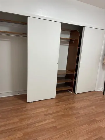 a view of an empty room with wooden floor and closet