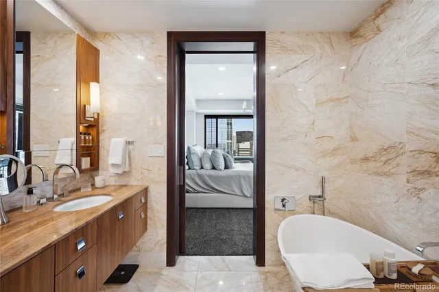 a en suite bathroom with a granite countertop tub sink and mirror