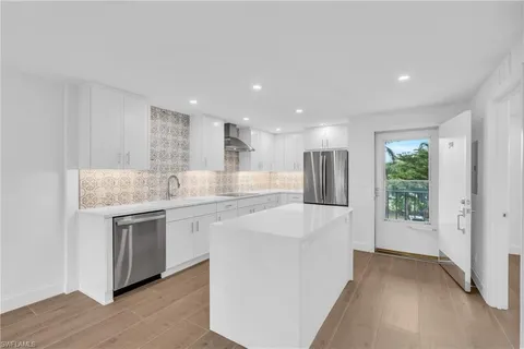 a large white kitchen with a sink and refrigerator