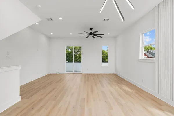 an empty room with windows and fan