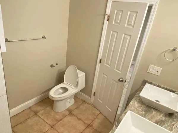 a bathroom with a granite countertop toilet and a sink