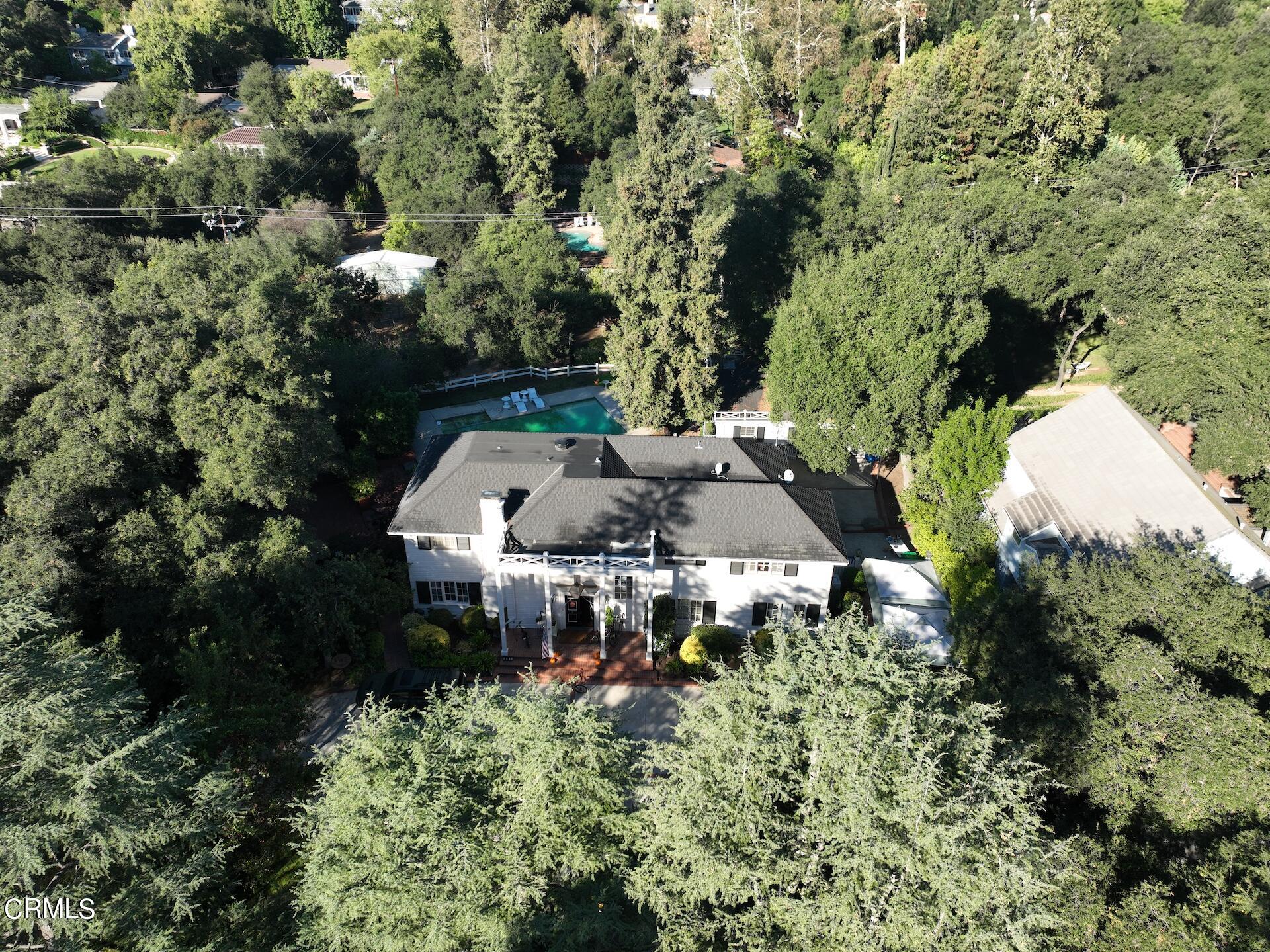 an aerial view of a house with a yard and large trees