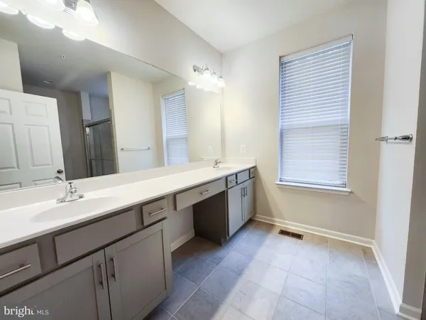a spacious bathroom with a double vanity sink a mirror and a bathtub