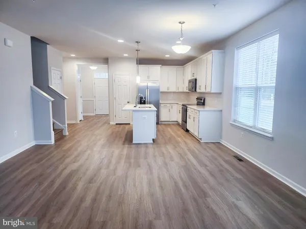 a large kitchen with a wooden floor and windows