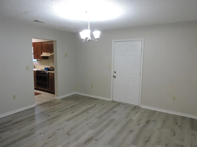 an empty room with wooden floor chandelier and entryway