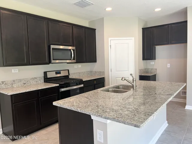 a kitchen with kitchen island granite countertop a sink counter top space and stainless steel appliances