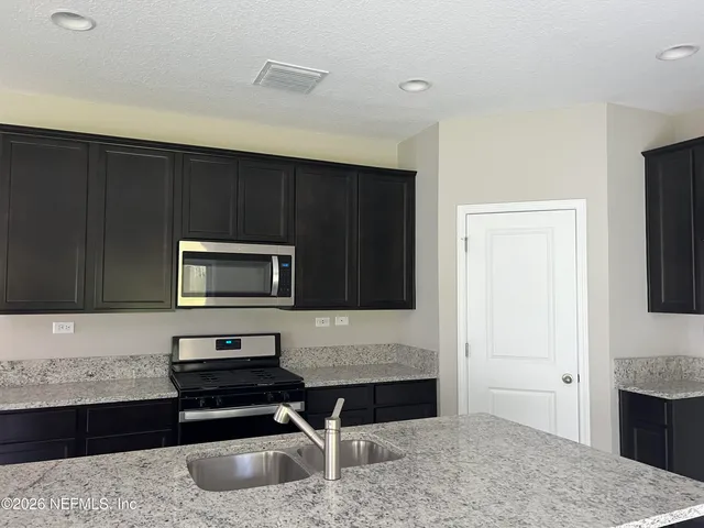 a kitchen with granite countertop a stove and a microwave oven