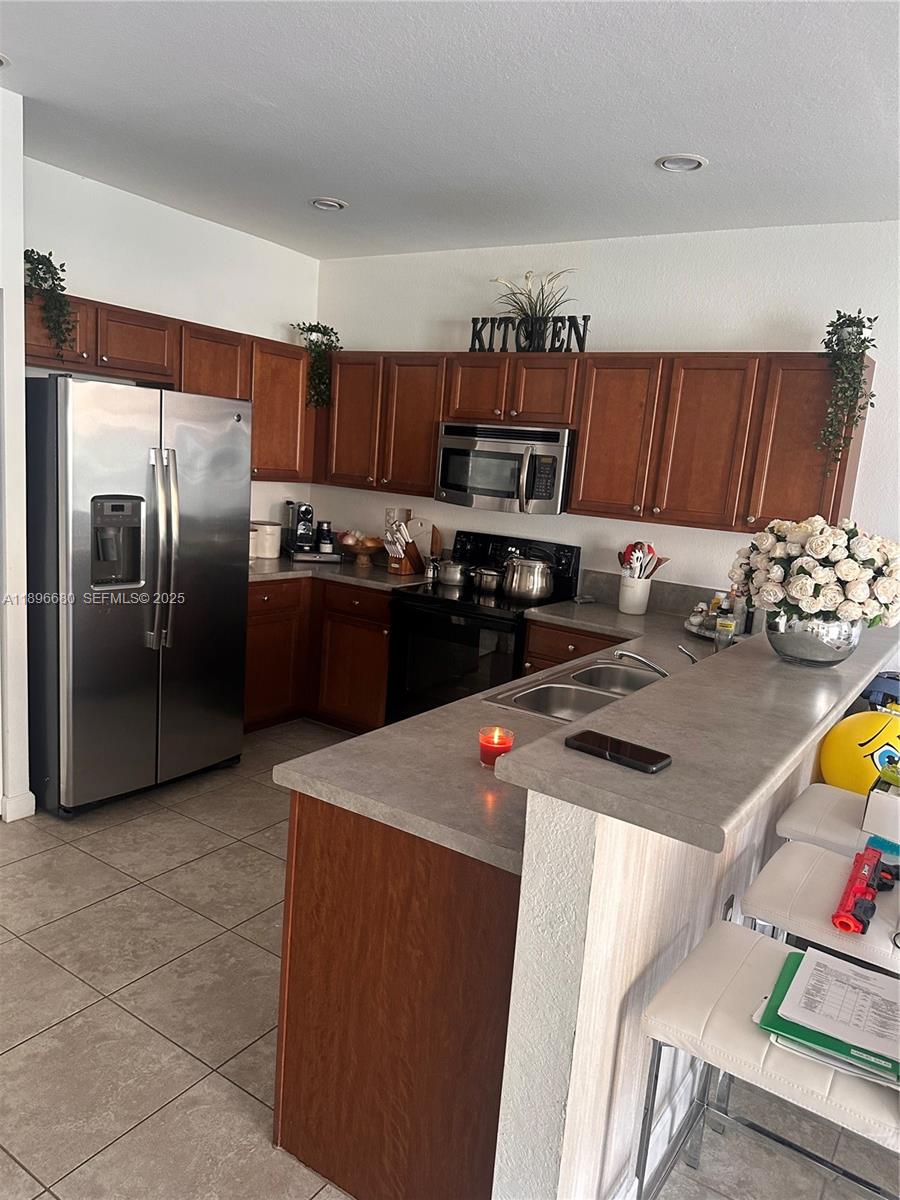 8867 West 35th Way Hialeah, FL 33018 - Photo 5 of 15 a kitchen with stainless steel appliances granite countertop a sink a stove a refrigerator and a refrigerator