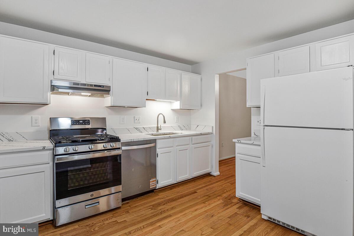 7865 Parthian Court Springfield, VA 22153 - Photo 7 of 40 a kitchen with granite countertop cabinets stainless steel appliances and wooden floor