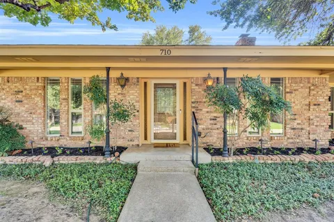 a front view of a house with a yard and potted plants