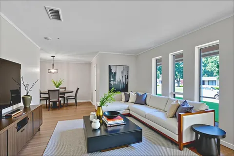 a living room with furniture potted plant kitchen view and a window