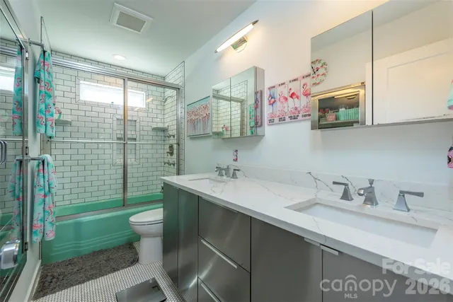 a bathroom with a granite countertop sink a toilet a shower and a mirror