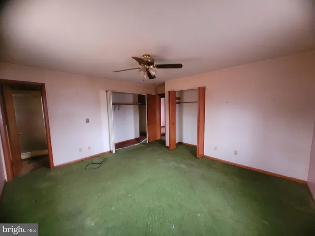 an empty room with closet and fan